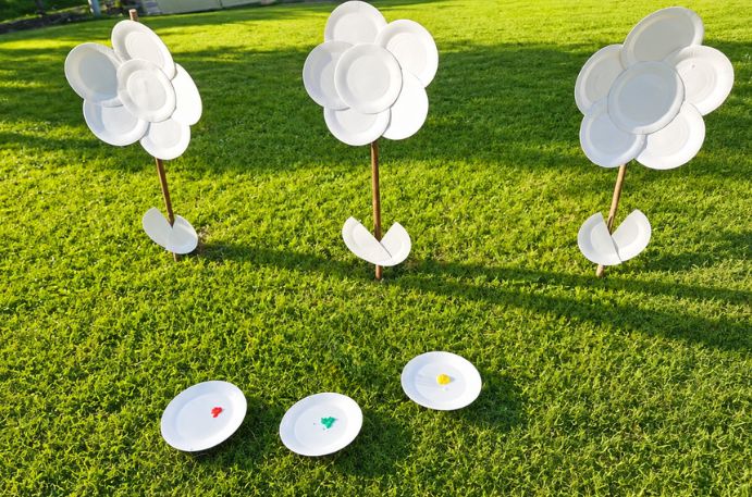 Flores hechas con platos de cartón pintadas por niños en un jardín